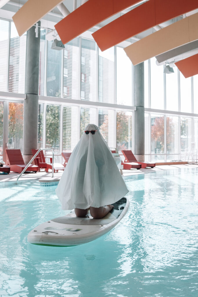 person dressed like a ghost floating on a stand up paddle board in the water