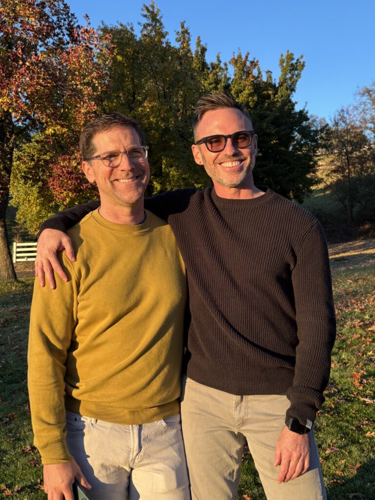 two men standing together at sunset